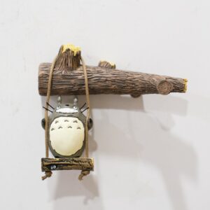 Miniatura do Totoro no balanço de corda sob um galho