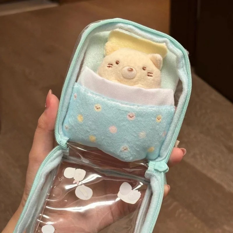 Bolsa transparente do Sumikko Gurashi aberta, mostrando o forro de PVC e a cama com cobertor azul