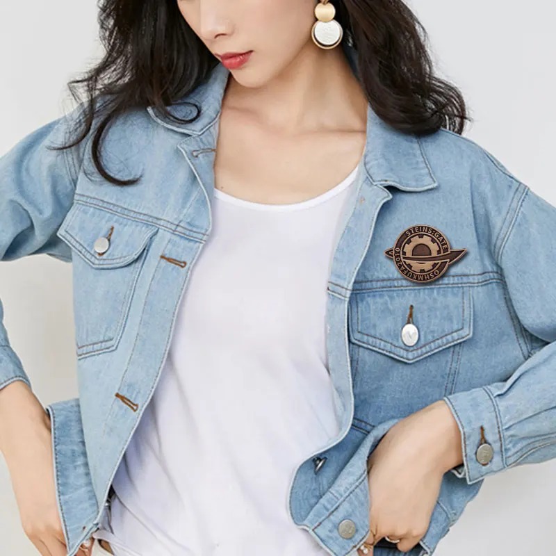 Mulher de jaqueta jeans com o broche de Steins;Gate preso no peito