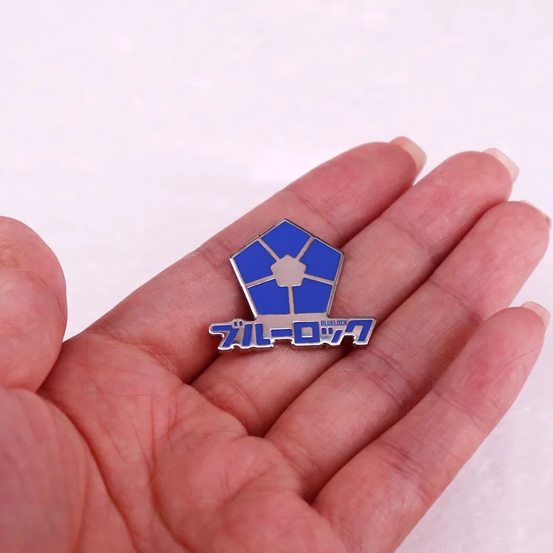 Broche do emblema de Blue Lock na palma da mão, mostrando o tamanho pequeno