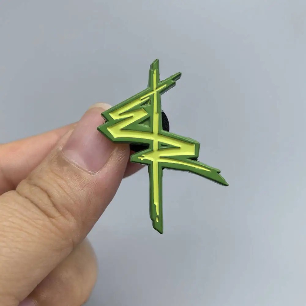 Broche do logo verde de Edgerunners entre os dedos, para mostrar o tamanho