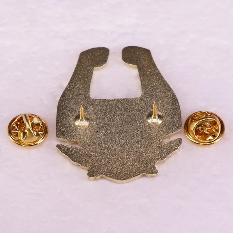 Parte de trás do broche da Midna, com dois pinos e fechos de borboleta dourados