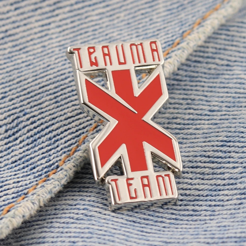 Broche da Trauma Team preso a um tecido jeans azul