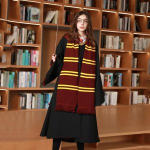 Mulher de cachecol listrado vermelho e dourado e capa preta diante de uma estante, estilo Hogwarts