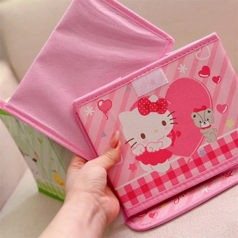 Mão erguendo a tampa da caixa rosa da Hello Kitty, estampada com ursinho e coração