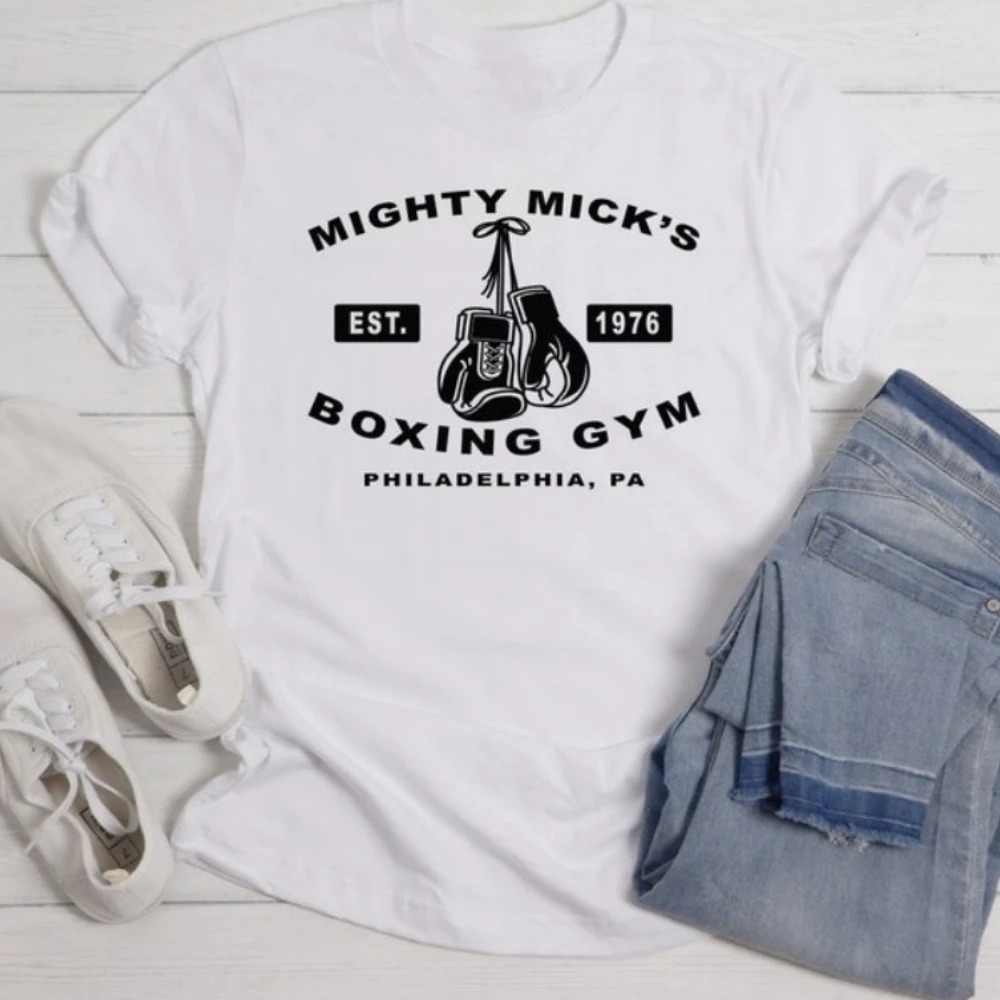 Camiseta branca com a estampa Mighty Mick's Boxing Gym, Est. 1976, e luvas penduradas