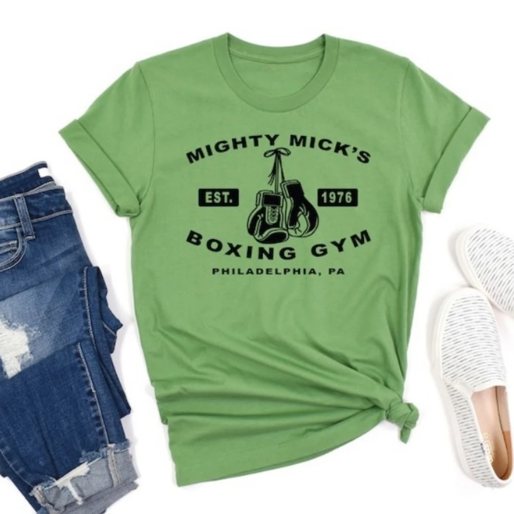 Camiseta verde com a estampa da academia, combinada com jeans e tênis