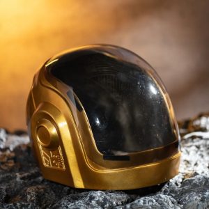 Capacete dourado de resina com viseira preta, estilo Guy-Manuel, sobre pedra