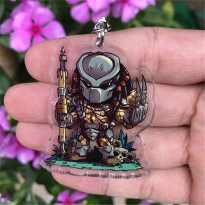 Chaveiro de acrílico chibi do Predador, com máscara metálica e lança, na palma da mão