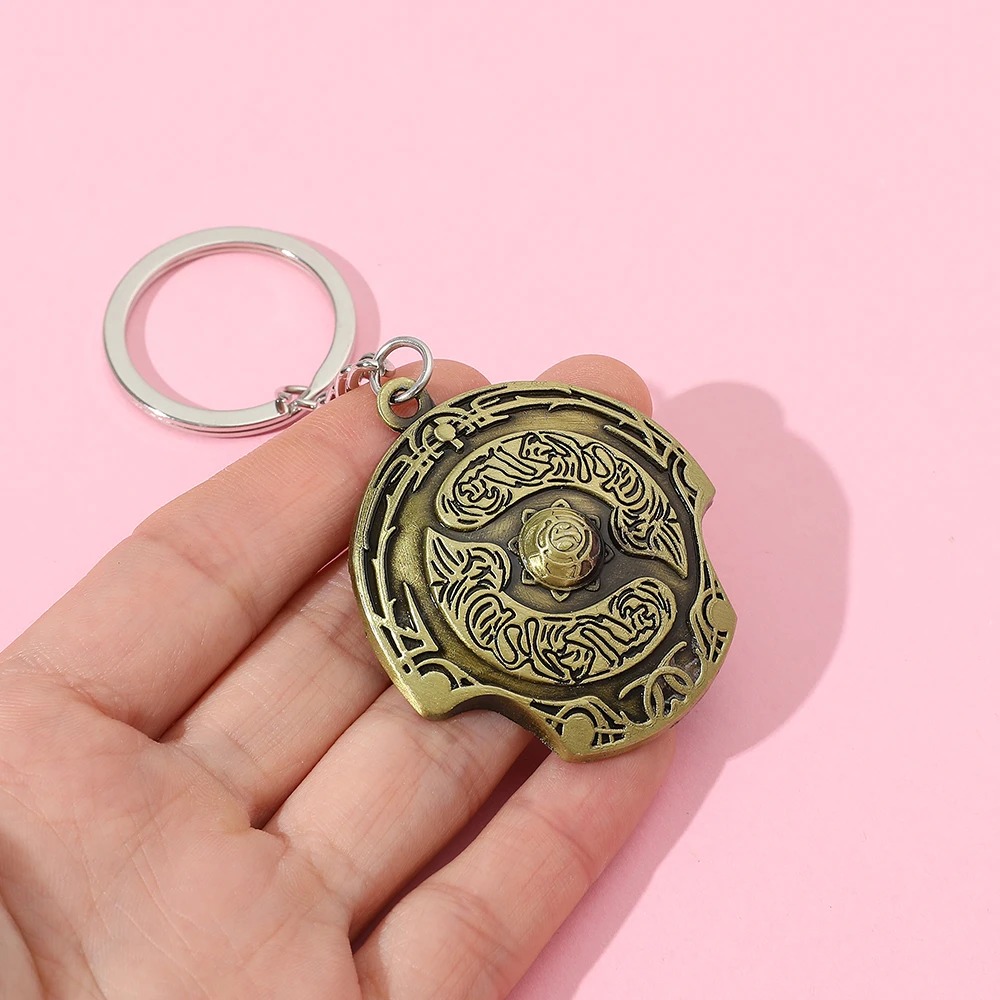 Chaveiro do escudo Aegis, de Dota 2, na palma da mão, mostrando o tamanho