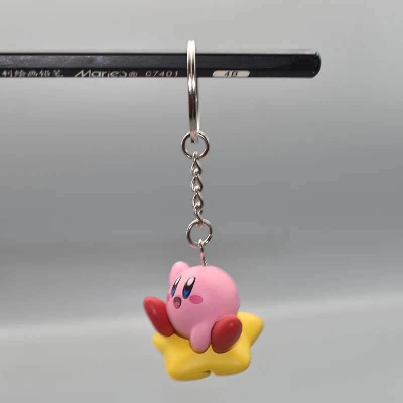 Chaveiro de figura do Kirby deitado na Estrela Dourada, preso a uma corrente com argola de metal