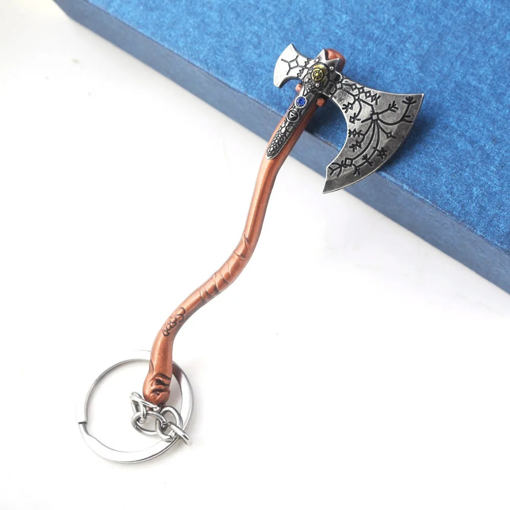 Chaveiro do machado do Kratos sobre fundo azul, com a lâmina decorada em destaque