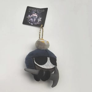 Zote de Hollow Knight em pelúcia mini, com capacete azul e capa cinza, preso numa corrente de bolinhas