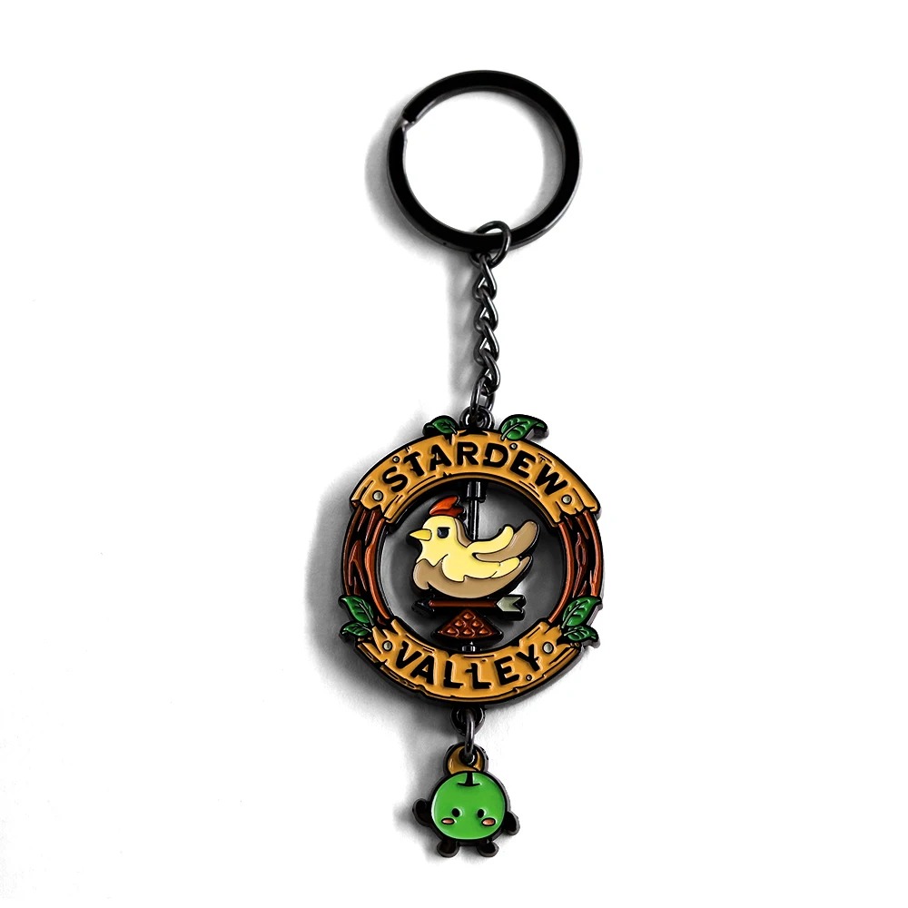Chaveiro de metal de Stardew Valley com placa redonda, galinha giratória e Junimo verde, em fundo branco