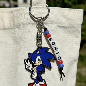 Chaveiro de metal do Sonic com contas formando SONIC, pendurado numa bolsa de pano