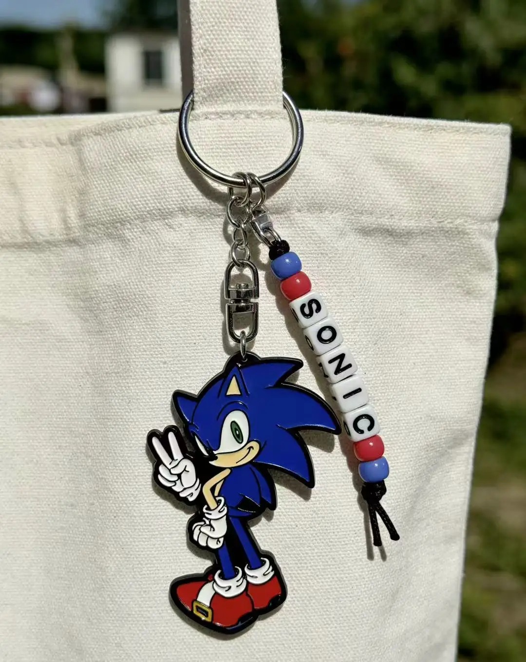 Chaveiro de metal do Sonic com contas formando SONIC, pendurado numa bolsa de pano