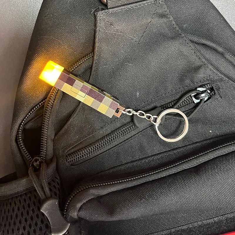 Chaveiro da tocha do Minecraft acesa, preso ao zíper de uma mochila