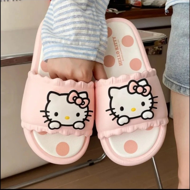 Par de chinelos slide rosa da Hello Kitty visto de cima, com sola de bolinhas
