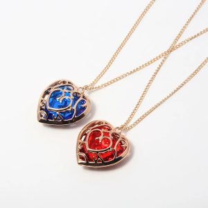 Dois colares de coração dourado de Zelda, de pedra azul e de pedra vermelha, sobre fundo branco