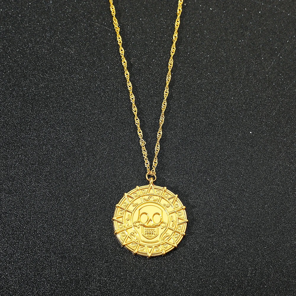 Medalhão dourado de caveira numa corrente fina sobre fundo escuro, Piratas do Caribe
