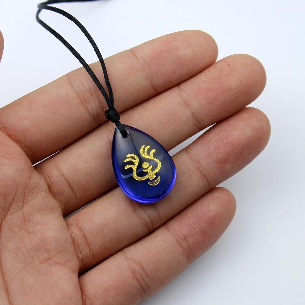 Pingente azul com símbolo dourado do colar da Sheeta, na palma da mão