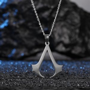 Colar prateado com o símbolo de Assassin's Creed sobre fundo de pedras escuras