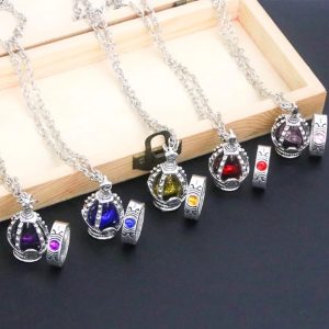 Cinco colares de soul gem com cristais de cores diferentes sobre uma caixa de madeira