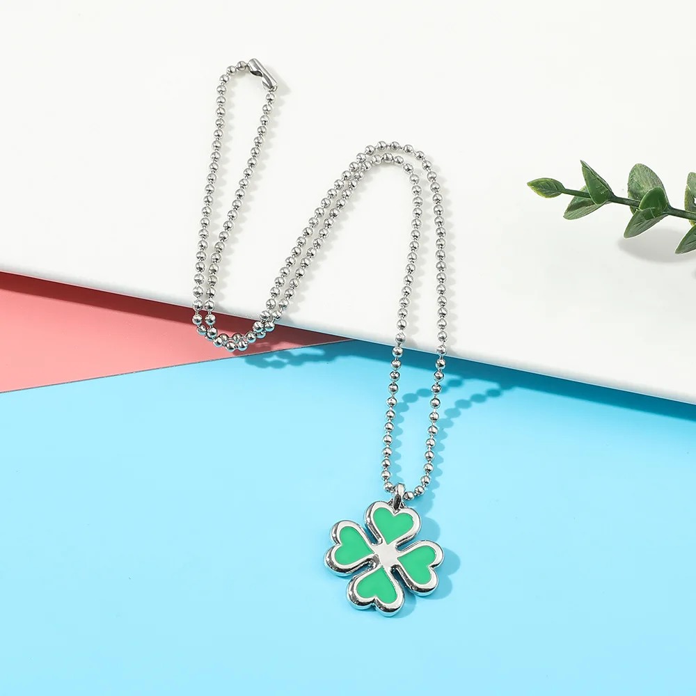 Colar de trevo de Tokyo Revengers com corrente de bolinhas, sobre fundo azul e rosa