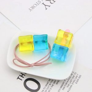 Elástico e presilha de cabelo com cubos azul e amarelo da Bocchi sobre um prato branco