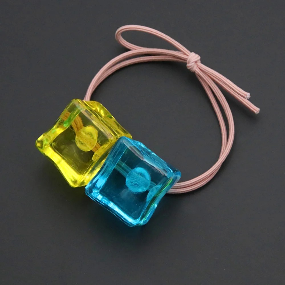 Elástico de cabelo rosa com dois cubos de resina azul e amarelo, da Hitori Gotoh