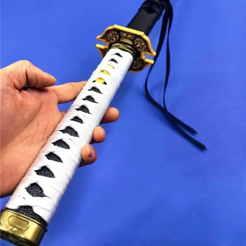 Mão segurando a empunhadura branca da Yamato, com guarda dourada e fitas pretas