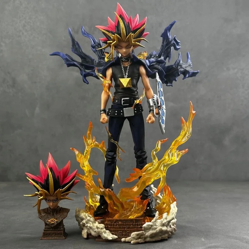 Yugi Muto de Yu-Gi-Oh! na base com chamas, capa azul, disco de duelo e a cabeça extra ao lado