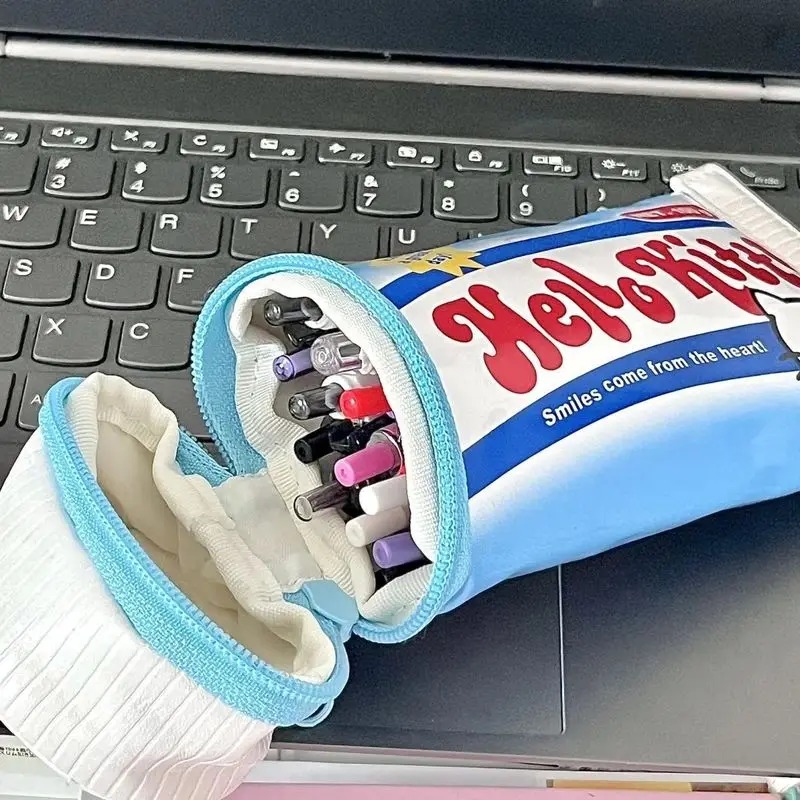 Estojo da Hello Kitty aberto, com canetas e lápis dentro, apoiado num teclado de notebook