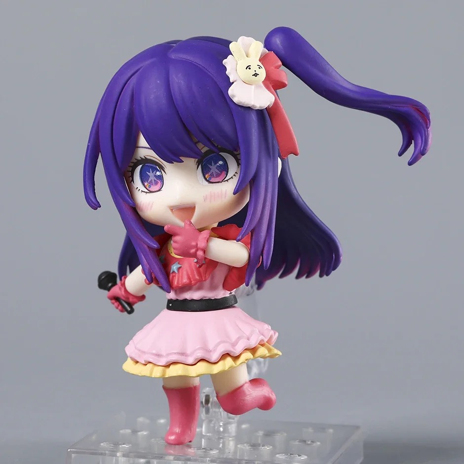 Figure chibi da Ai Hoshino com microfone, cabelo roxo e vestido rosa de idol, em pose de palco
