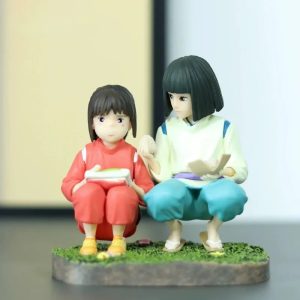 Chihiro e Haku agachados lado a lado numa base de grama, figure de A Viagem de Chihiro