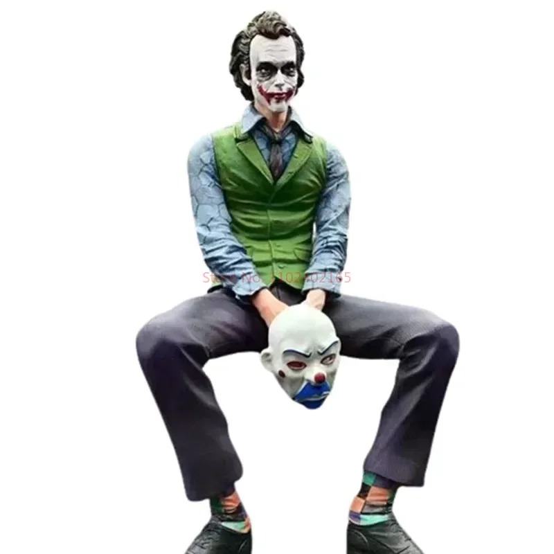 Coringa sentado de colete verde, segurando uma máscara de palhaço, figure de Batman: O Cavaleiro das Trevas