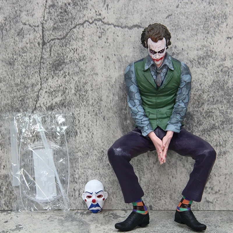 Figure de 24 cm do Coringa sentado e apoiado na parede, com a máscara ao lado