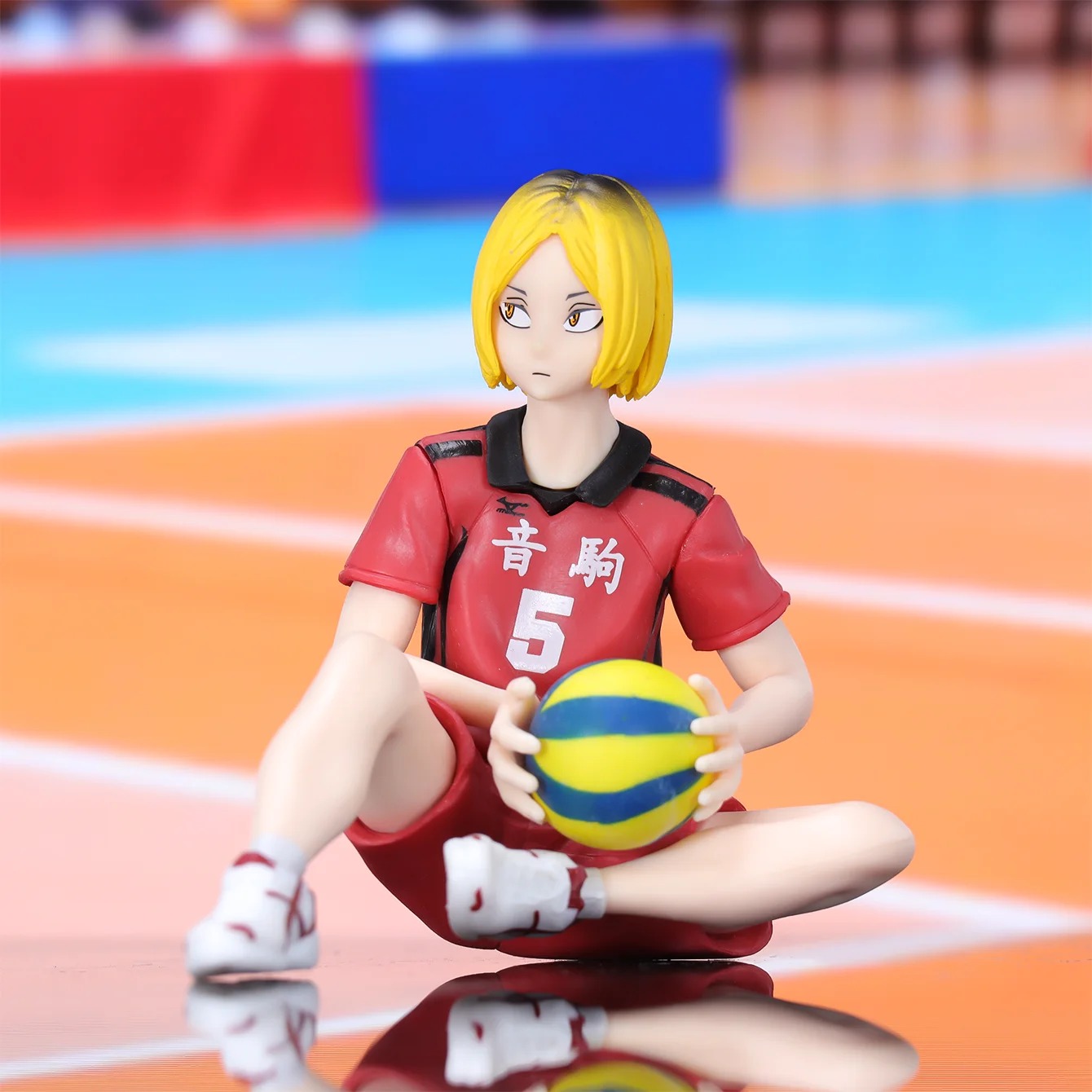 Figure do Kenma, de Haikyuu!!, sentado com a camisa vermelha do Nekoma e uma bola de vôlei, em close
