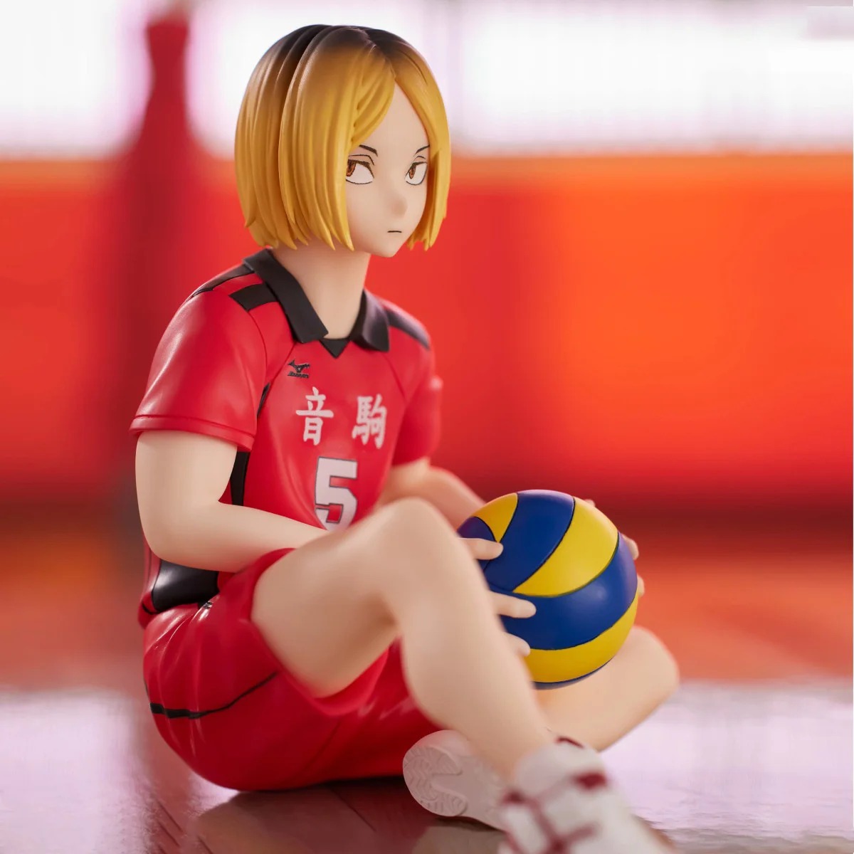 Figure do Kenma Kozume, de Haikyuu!!, sentado no chão da quadra com a bola no colo, de frente