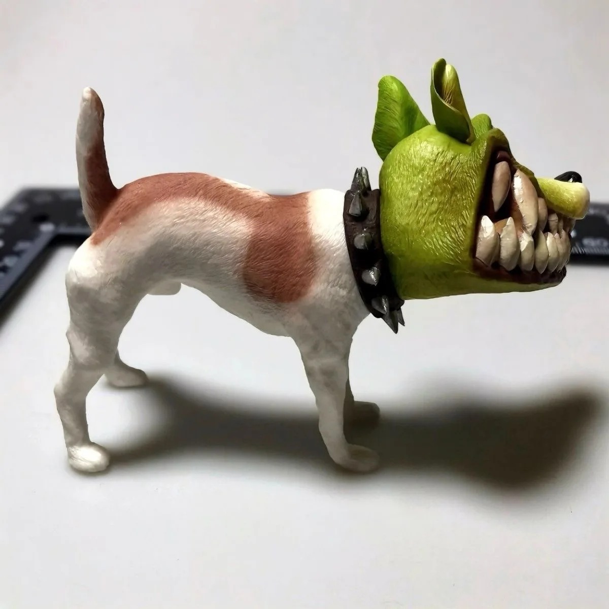 Figure do Milo, O Máscara, de perfil, com pelo branco e marrom, máscara verde e coleira de espinhos