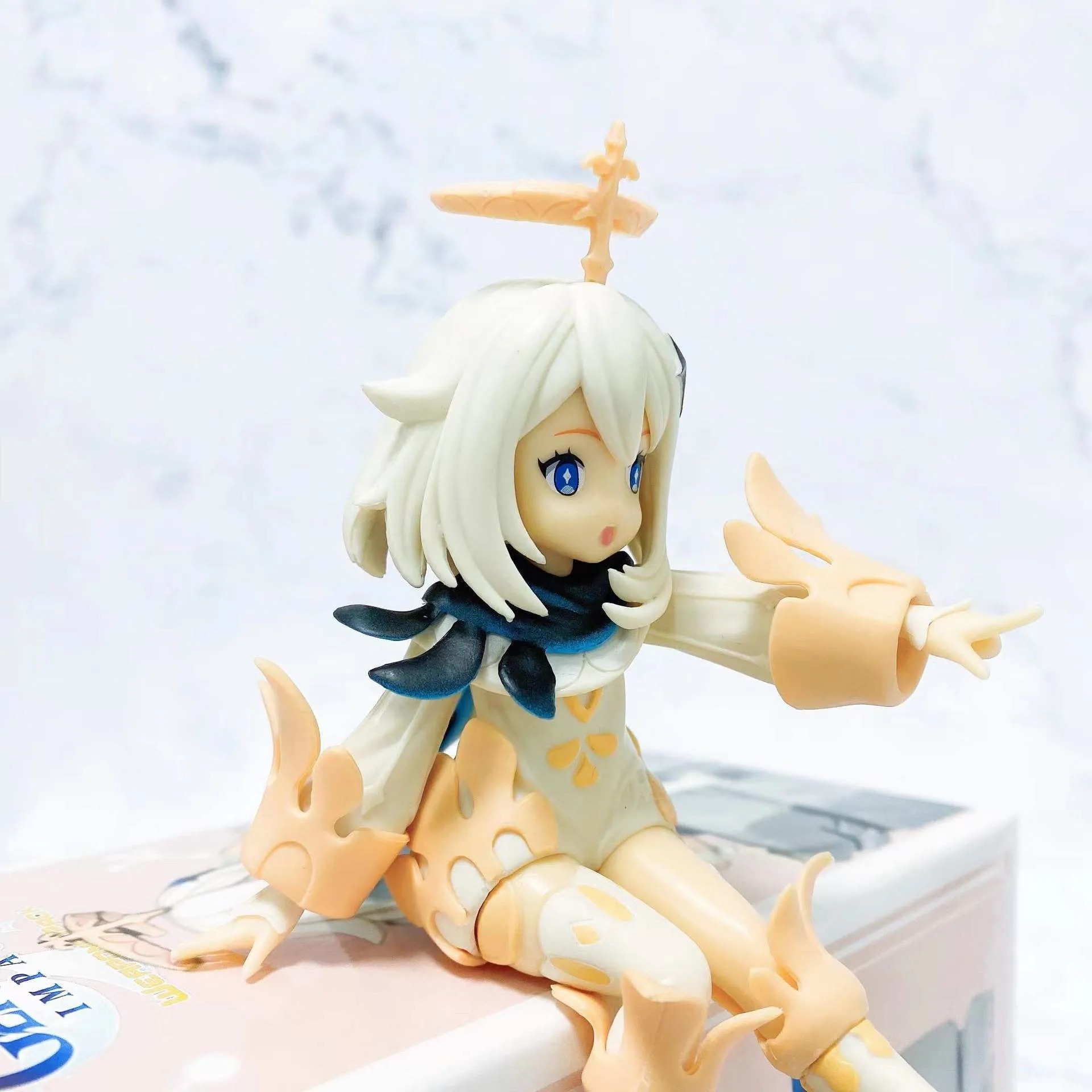 Paimon, de Genshin Impact, em detalhe da figure, com o halo e o vestido branco de detalhes dourados