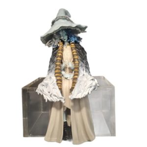 Figure da Ranni sentada num cubo acrílico, com chapéu de bruxa e tranças, sobre fundo branco, de Elden Ring