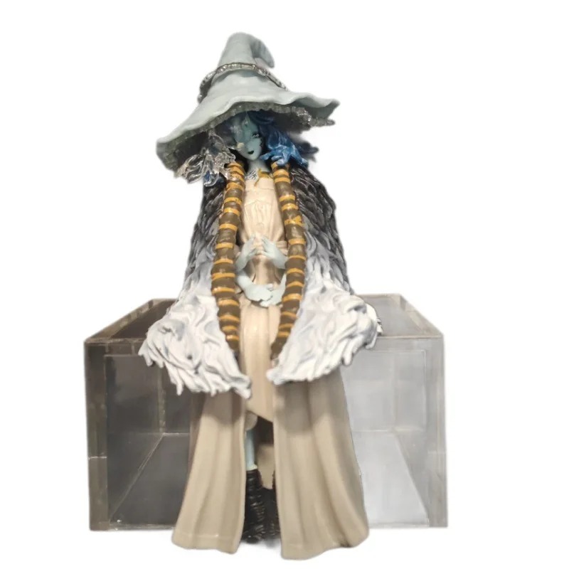 Figure da Ranni sentada num cubo acrílico, com chapéu de bruxa e tranças, sobre fundo branco, de Elden Ring