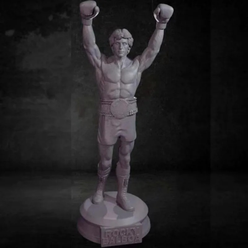 Miniatura de resina do Rocky de braços erguidos, calção e cinturão, sobre fundo escuro