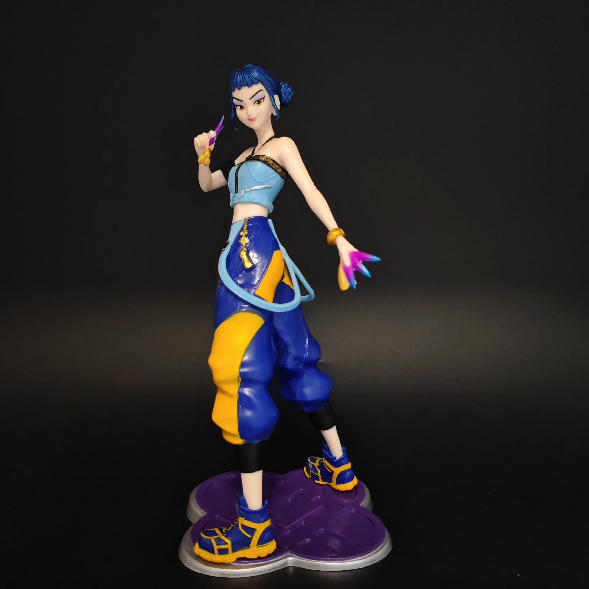 Zoey, de Guerreiras do K-Pop, em figure de cabelo azul, regata azul e calça larga azul e amarela, sobre base roxa