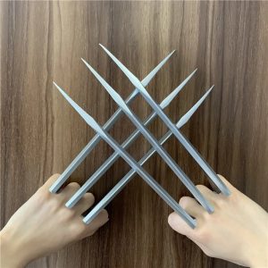 Garras prateadas de plástico, estilo Wolverine, cruzadas diante das mãos sobre madeira