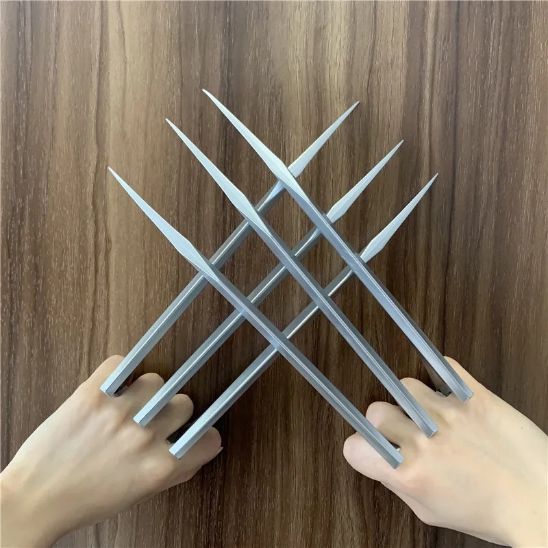 Garras prateadas de plástico, estilo Wolverine, cruzadas diante das mãos sobre madeira