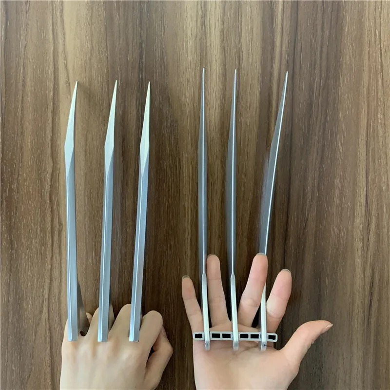 Garras de plástico prateado presas aos dedos, ao lado da outra mão aberta