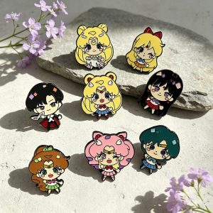 Kit de 8 pins chibi esmaltados de Sailor Moon, guerreiras e Tuxedo Mask, sobre uma pedra