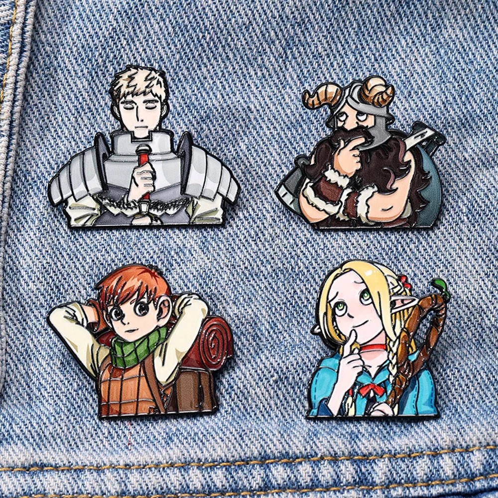 Os quatro pins de Dungeon Meshi presos em um tecido jeans